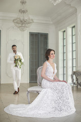 Chic wedding couple groom and bride posing in a white Studio. Happy couple laughing. White dress....