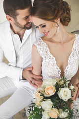 Chic wedding couple groom and bride posing in a white Studio. Happy couple laughing. White dress....