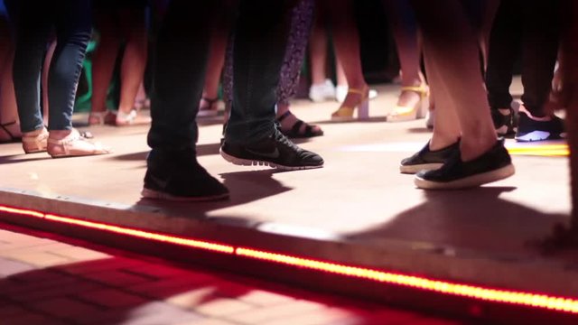 People dance in a nightclub with a bright light