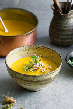 Carrot soup: A stoneware bowl with carrot soup garnished with micro sprouts.
