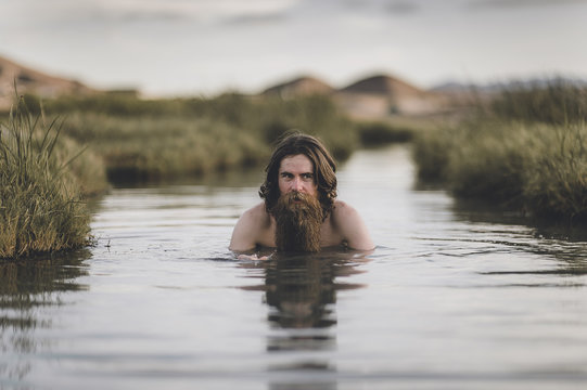 A handsome bearded man with his dogs in beautiful desert hot springs during the golden hour