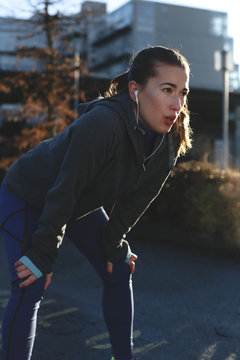 Young, healthy caucasian woman breathing hard outside during running workout