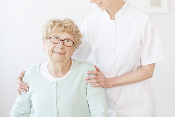 Nurse hugs smiling elderly lady