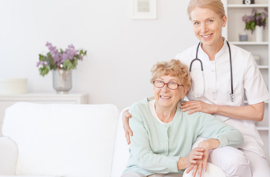 Smiling nurse sits with elder woman