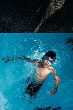Top view action shot of a young swimmer doing backstroke about to finish