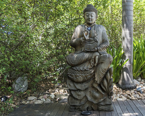 Wooden buddha statue with green trees as background
