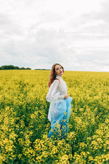 Naklejka na ściany i meble Beautiful girl in a dress among yellow flowers in a field