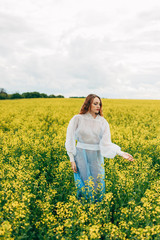 Fototapeta premium Beautiful girl in a dress among yellow flowers in a field