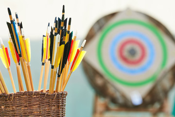 Archery concept. Basket with arrows in front of target.