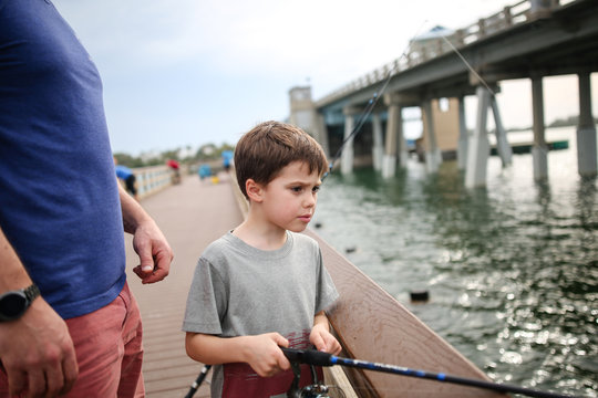 Young Boy And Father  Fishing From Wooden Jetty