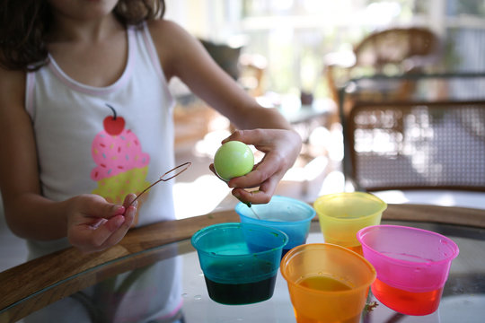 Young girl dyeing easter eggs