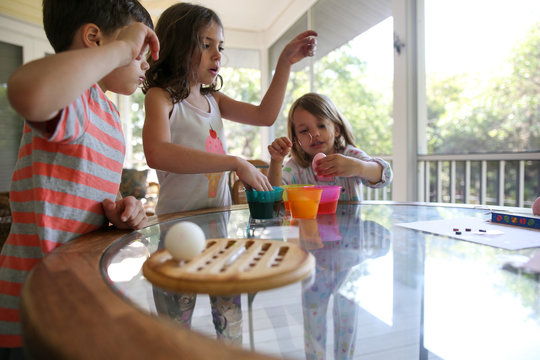 Three children decorating and dyeing easter eggs