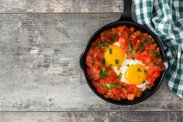 Shakshuka in iron frying pan on wooden table. Typical food in Israel.

