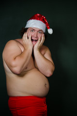 Funny guy without a shirt in a Santa suit. Cheerful fat Santa Claus. 