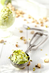Pistachio ice cream with crushed nuts on the white wooden background - 167483623