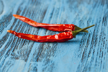 Two red hot peppers on blue wooden background