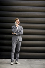 Handsome businessman with mobile phone by office building