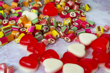 Scattered colorful sweetmeats and red white candied fruit jelly close up