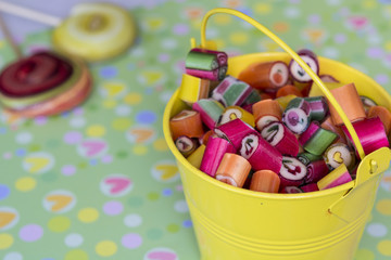 Many bright colorful sweetmeats in small yellow bucket