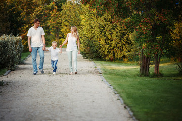 Fototapeta premium Happy young family walking on path in Park holding hands.