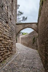 Fototapeta na wymiar a stone road in a medieval city of Carcossone with stone walls on both sides and a arch