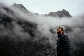 Man in his down jacket looking towards the cold foggy sky as the weather changes