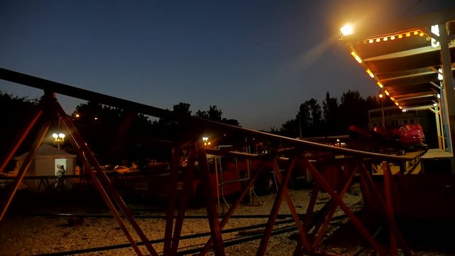 Girl teenager rolls on roller coaster at night. Amusement roller coaster night holiday