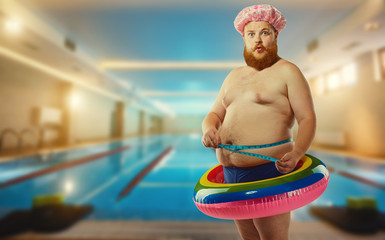 Funny man in inflatable circle at the pool