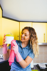 Beautiful young smiling woman cleaning in kitchen with microfiber cloth. 