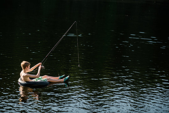 child on float in lake with fishing rod