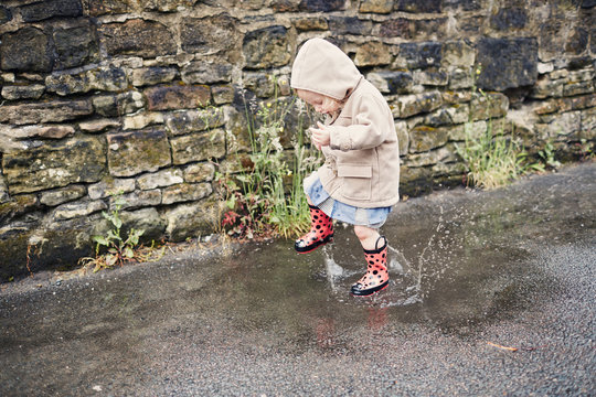 Child playing in the puddles on a rainy day