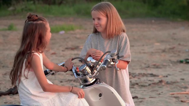 Children have amicably fun on vacation. The moped the sea. Two little girls have fun on the beach at water.