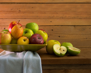 Pile of fresh apples in the green wooden tray on the wooden plank and old wooden wall