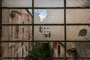 Abandoned factory through broken window.