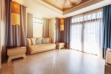 Living room in tropical Villa Hotel. Big windows, glass doors and garden outside