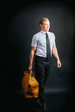 Traveling businessman with yellow bag. Studio portrait, black background