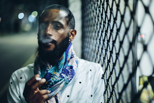 Portrait of smoking man with cigarette outdoor. Mixed race black skin and beard