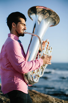 Outdoor Portrait of musician with tuba wind musical instrument. Atlantic Ocean beach