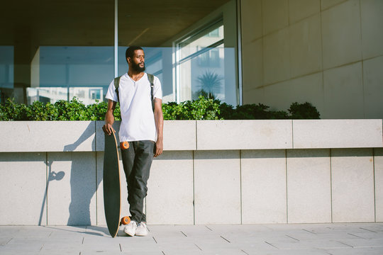 Portrait of man with skate board outdoor. Mixed race black skin and beard. Summer sport activity
