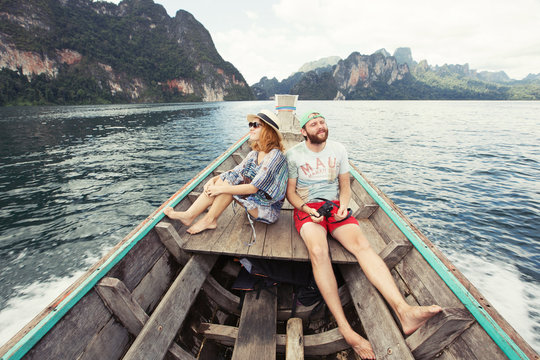 Young couple travel on boat on tropical mountain lake