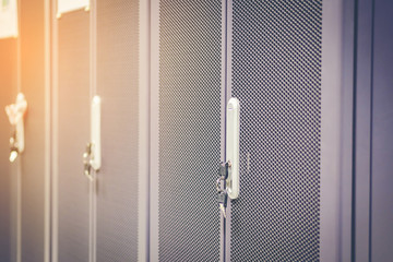 Black metallic door of server rack cabinet. The key is inserted into the door lock. Side lighting.