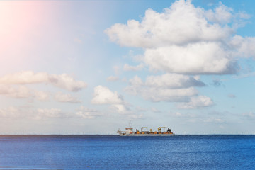 large container cargo ship on wide blue ocean under sunny sky
