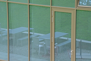 Gartenmöbel spiegeln sich in Glasfassade