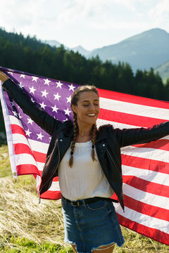 A young woman holding an American flag outdoors