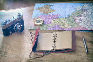 Traveler's things: old camera, map, notebook, compass on a wooden background