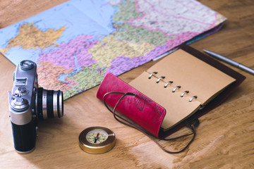 Traveler's things: old camera, map, notebook, compass on a wooden background
