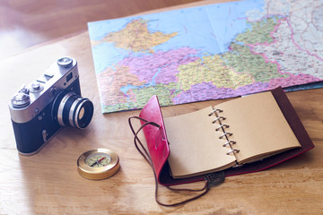 Traveler's things: old camera, map, notebook, compass on a wooden background