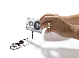 Using pencil to spin mangled cassette tape isolated on white background. 
