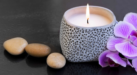 Spa candle setting with massage stones and orchid flower