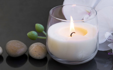 Spa candle , wellness and spa setting with massage stones and white orchid